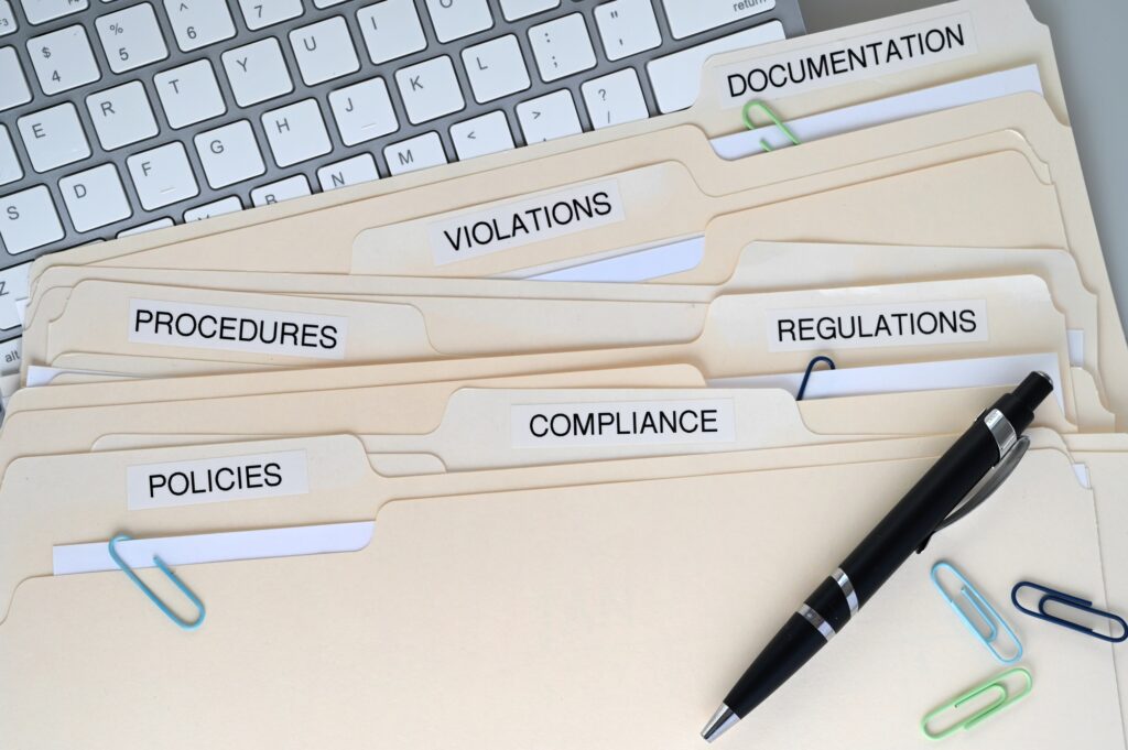 website legal policies - Compliance, Policies, Regulations, Violations, Procedures and Documentation folders on a desk